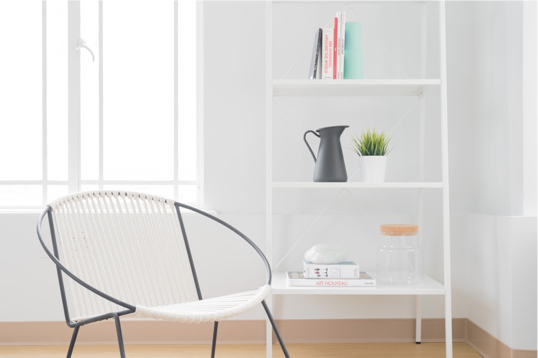 a white day chair with a bookshelf behind